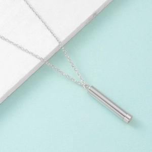 Macro shot of silver cylindrical stainless steel pendant on a delicate O-link chain