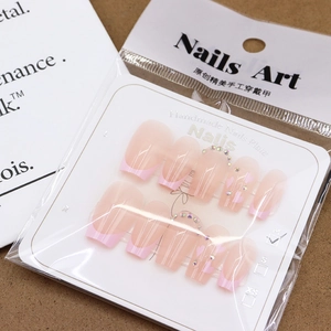Handmade pink French press-on nails with heart accents and rhinestones on display card