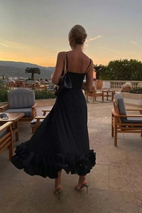 Detail of elegant black A-line midi dress with ruffled hem and chic backless design