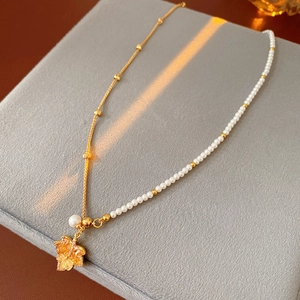 Détail du pendentif feuille d'érable doré avec zircons et perles sur un coffret