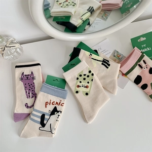 Flat lay of cotton crew socks with cute cartoon cat patterns and colorful heel details