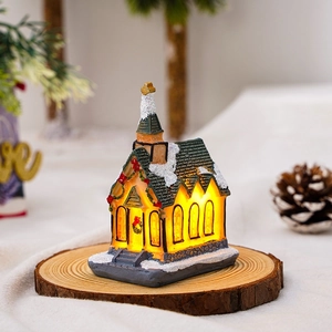 Close-up of glowing resin Christmas snow house on wooden base with warm led lights