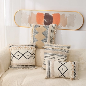 Close-up of bohemian tufted pillow covers with black geometric patterns and tassels