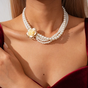 Dettaglio di collana di perle multistrato con ciondolo a fiore in resina e strass brillanti