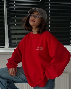 Detail of red crewneck sweatshirt with white letter embroidery and dropped shoulders