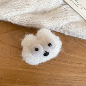 Detail of plush white bear brooch with black eyes on a cozy knitted sweater background