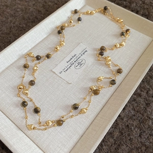 Detail of 18k gold plated necklace with tiger eye beads and pearls on vintage card