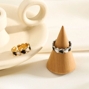 Detail of heart enamel rings in gold and silver finish with black and white drip oil patterns