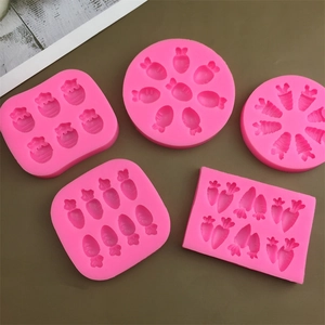Macro detail of various pink silicone carrot and strawberry molds on a wooden desk surface