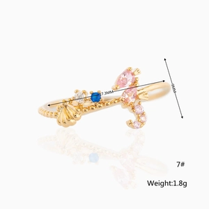Detail showing seahorse and shell design with colorful zircons on a golden ocean ring
