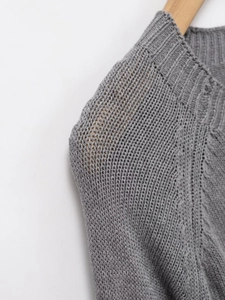 Detailopname van de halslijn en schoudernaden van de grijze gebreide trui op een hanger