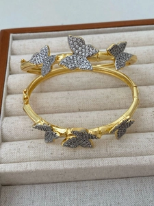 Close-up of dual gold butterfly bracelets with micro-pave cubic zirconia on velvet