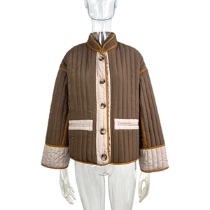 Close-up of brown quilted jacket featuring contrast beige piping and tortoiseshell buttons