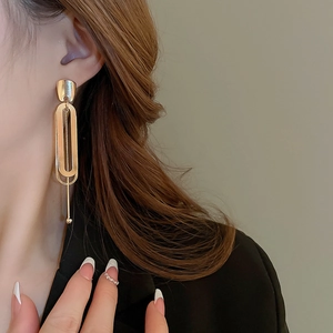 Close-up of golden geometric double-layer oval chain earrings on model with metal finish