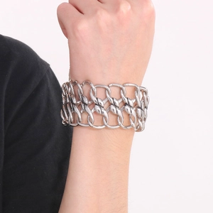 Close-up of a layered silver chunky metal chain bracelet with woven mesh and industrial links