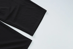 Detail view of the black trousers leg hem showing high-quality double stitching craft