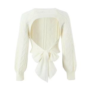 Off-white cable knit backless sweater with a large decorative bow and lantern sleeves