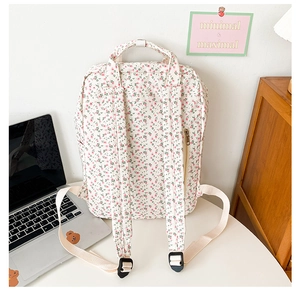 Floral canvas backpack with adjustable straps and top handle in a lifestyle setting