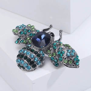 Detailed view of vintage bee brooch with blue crystal and colorful rhinestones