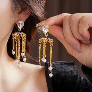 Detailed view of vintage gold tassel earrings with clear crystal drop and small white pearls
