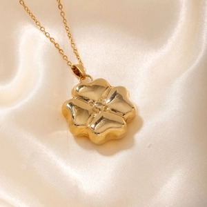 Elegant gold hollow flower pendant necklace on minimalist chain with silky background