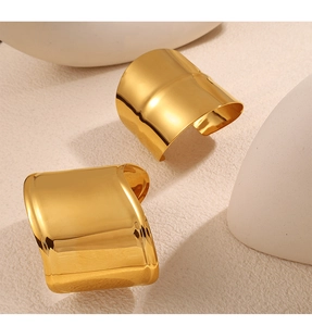 Macro view of a wide gold cuff bracelet featuring a polished irregular surface design