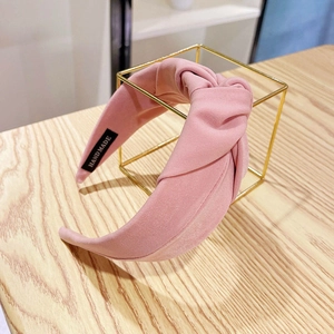 Detail of pink fabric headband with twisted knot design and handmade label on wood