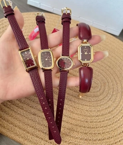 Detailed display of four burgundy leather strap watches with gold metal cases on a hand
