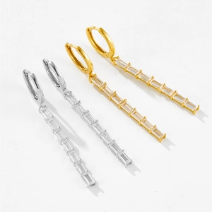 Dettaglio di orecchini pendenti in argento e oro con zirconi rettangolari scintillanti