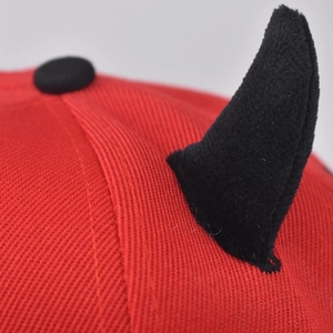 Detailed close-up of the black plush horn attachment on the red hip-hop baseball cap