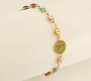 Macro view of gold chain bracelet with colorful evil eye charms and letter K pendant