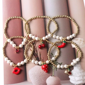 Detail of beaded bracelets featuring red cherry, strawberry, and heart charms with pearls