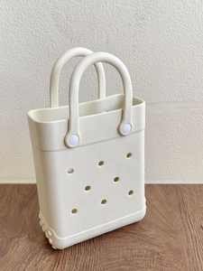 Detailed view of the white EVA beach bag with durable hole design on a wooden surface