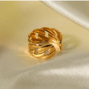 Detailed close-up of a 18K gold-plated stainless steel chain-link ring on beige silk fabric