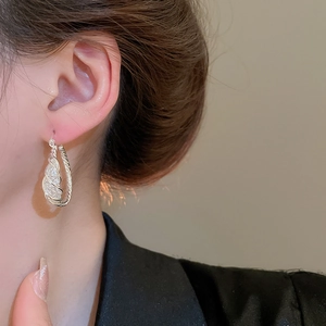 Close-up of a silver twisted hoop earring with pave zircons on a female model's ear