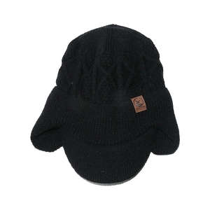 Détail du bonnet en tricot noir avec protège-oreilles et écusson en cuir de cerf