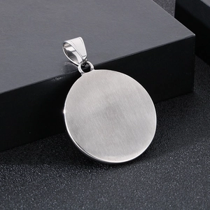 Macro shot of a round silver brushed stainless steel pendant on a black texture box