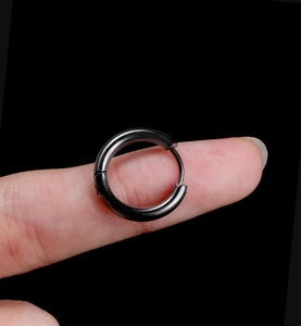 Macro view of black titanium steel hoop earring held on finger to show the precise product size