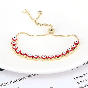 Detailed view of the red evil eye beads and adjustable slider buckle on gold bracelet