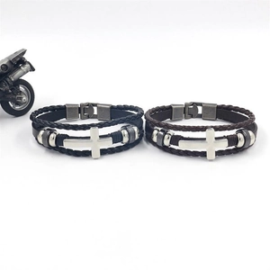 Detail of hand-woven leather bracelets in black and brown with silver cross charms