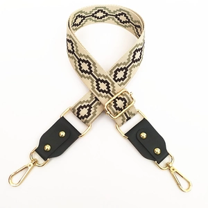 Detail of jacquard strap with geometric patterns and leather ends with gold hardware