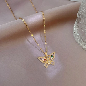 Detail of gold butterfly pendant with colorful gemstones and crystals on purple silk fabric
