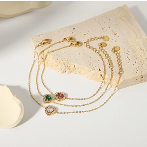 Detailed close-up of 18K gold-plated heart bracelets with green, red, and clear crystals