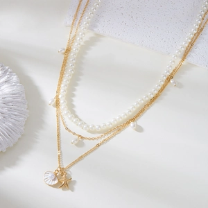 Multilayer gold necklace set with pearls, white shell and starfish charms on beach decor