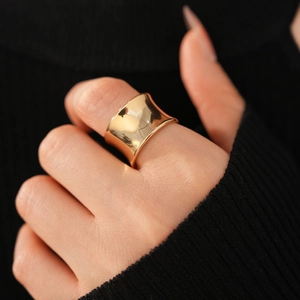 Detailed view of wide concave golden ring with high-polished metallic finish on hand