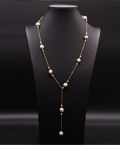Detail of a long gold-plated Y-necklace featuring luminous natural freshwater pearls