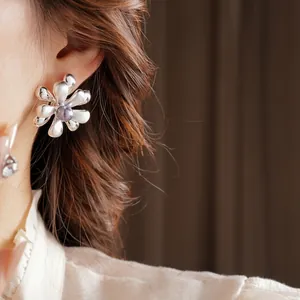 Silver flower stud earrings with purple center bead worn by a model in luxury style
