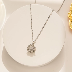 Macro shot of silver rotating snowflake pendant necklace with rhinestones on a white stand