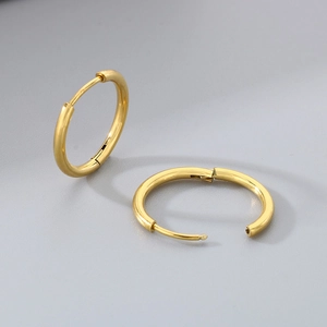 Detailed view of gold stainless steel hoop earrings with hinge mechanism on gray background