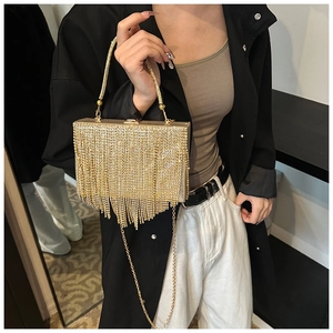 Elegant gold evening clutch bag with long rhinestone tassels held by a model in black coat